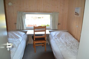 Ein Zimmer mit zwei Betten, einem Holztisch und einem Stuhl.