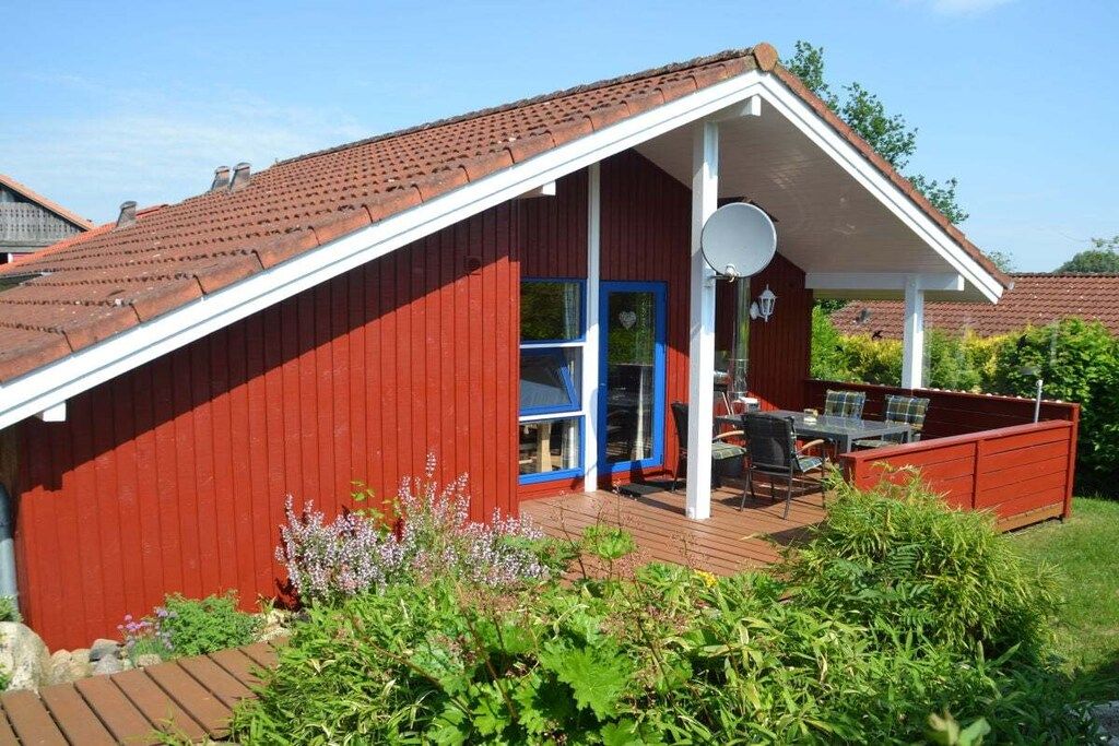 A red building with a white porch and a satellite dish.