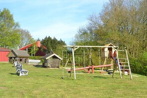 Ein Spielplatz mit Schaukeln, einer Rutsche und einer Kletterkonstruktion.