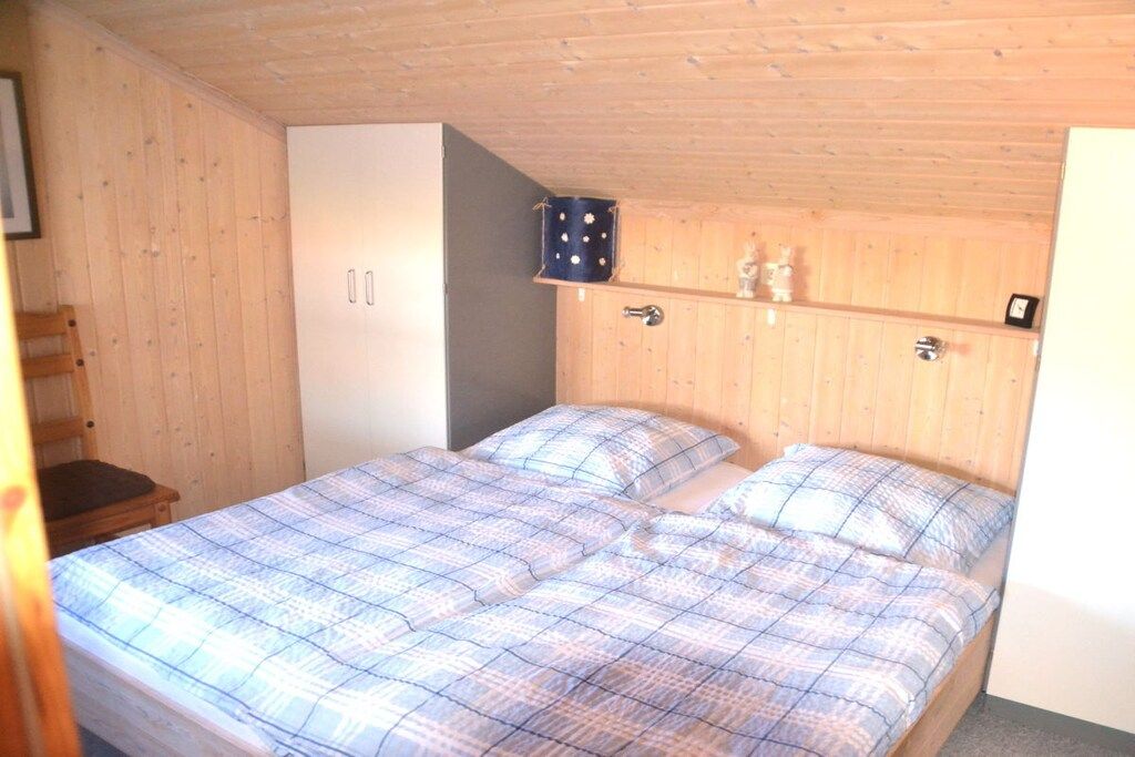 A bedroom with a bed, a wardrobe, and a shelf with decorative items.