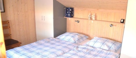A bedroom with a bed, a wardrobe, and a shelf with decorative items.