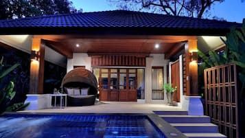 A modern outdoor pool area with a hot tub, wooden pergola, and a covered seating area.