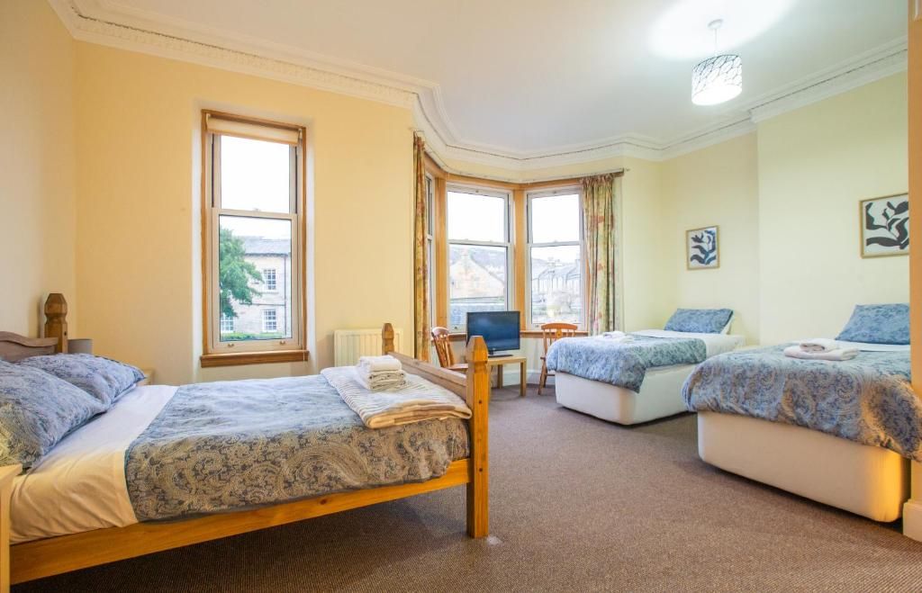 A hotel room with two beds, a desk, a chair, and a television.