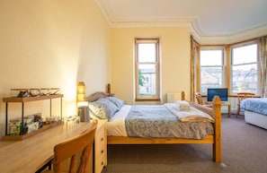 Une chambre à coucher avec un lit, un bureau avec une lampe, une chaise, un téléviseur et une fenêtre donnant sur un beau paysage.