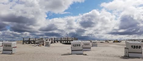 A beach with numbered containers, a wooden fence, and a clear sky.