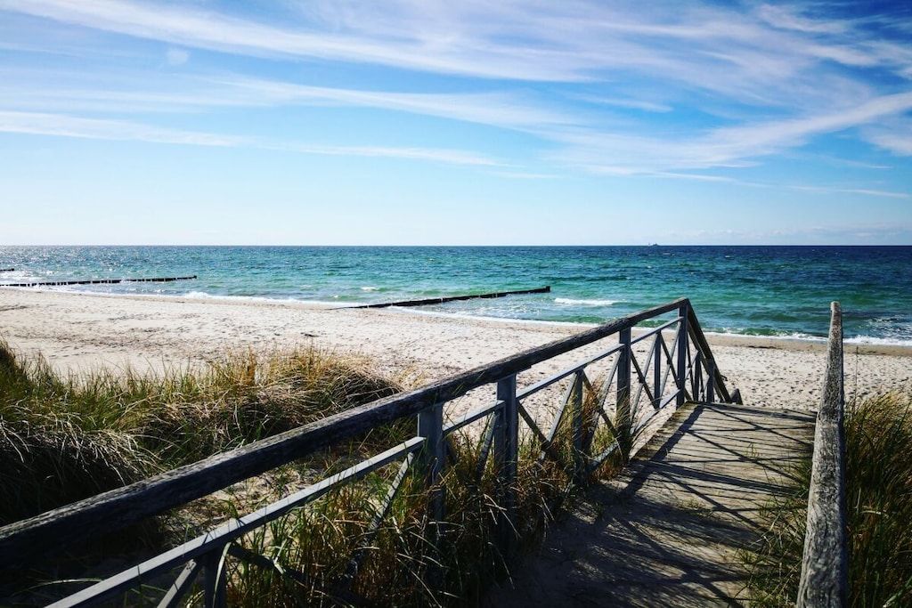 A wooden boardwalk leading to a sandy beach with the ocean in the background.