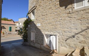 A stone building with a narrow street, a small window with shutters, and a sign indicating a street name. - Studio dans maison de village (Casalabriva)