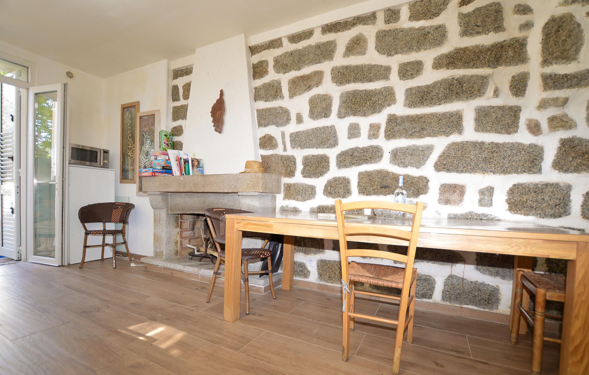 Un comedor con pared de piedra, mesa de madera y dos sillas.