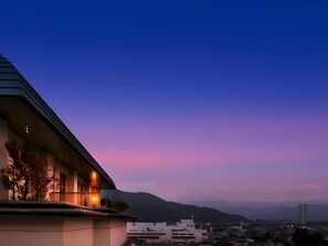 A modern building with a sloped roof and a balcony overlooking a cityscape at dusk. - Kami No Yama Azumaya (Kaminoyama)