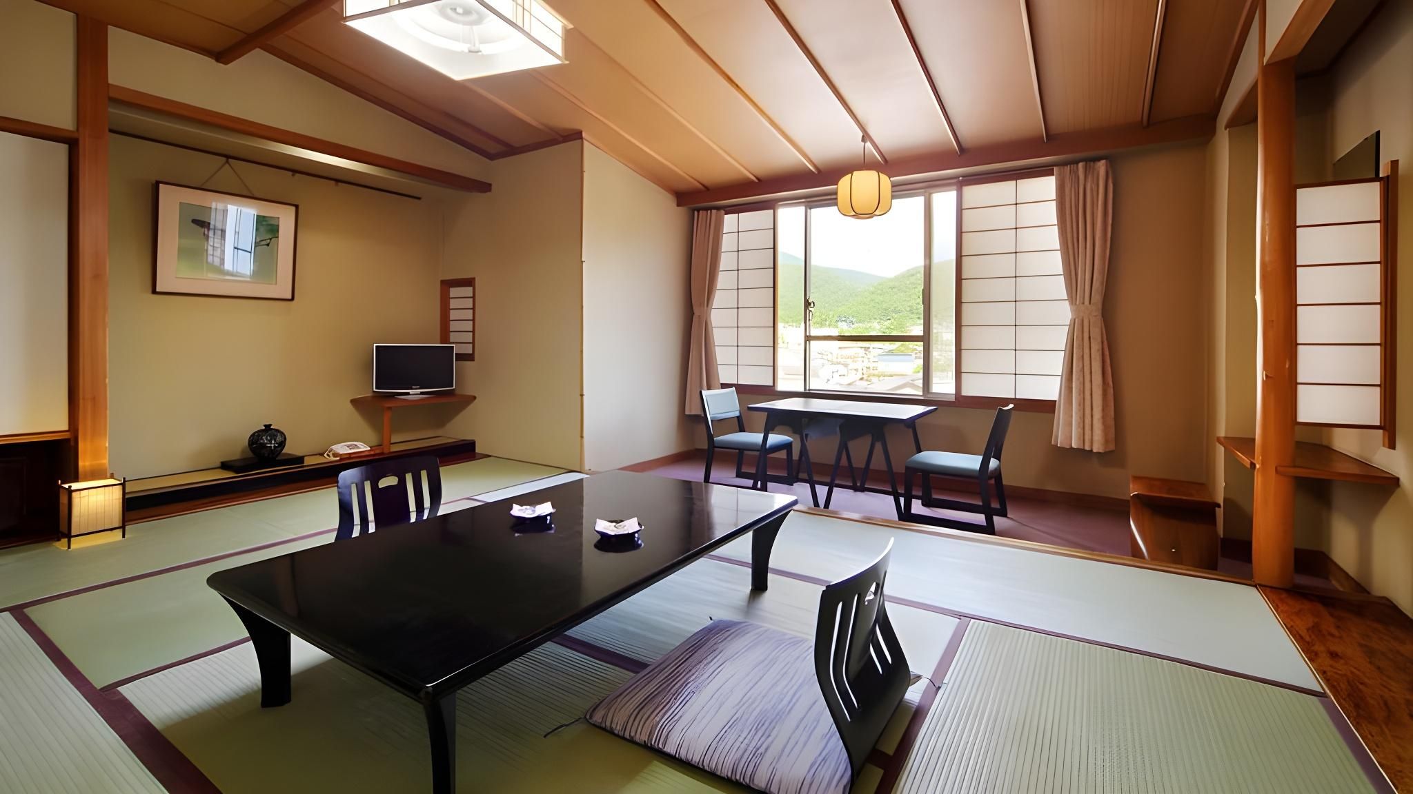 Una habitación de estilo japonés tradicional con suelo de tatami, una mesita baja y puertas correderas.