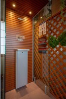 A room with a wooden slatted wall, a small white cabinet, and a glass partition with a wooden lattice design.