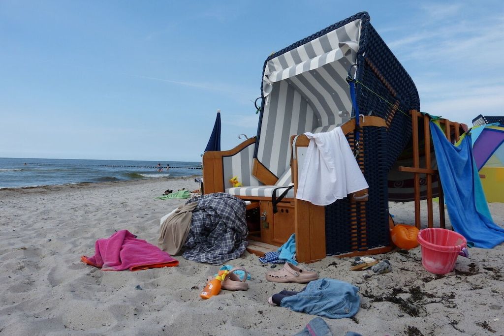 A beach chair with a striped canopy, a pink towel, and a beach umbrella.