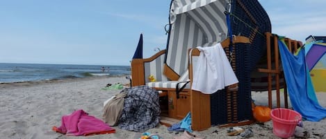 Une chaise de plage avec un parasol à rayures, une serviette rose et un parasol de plage.