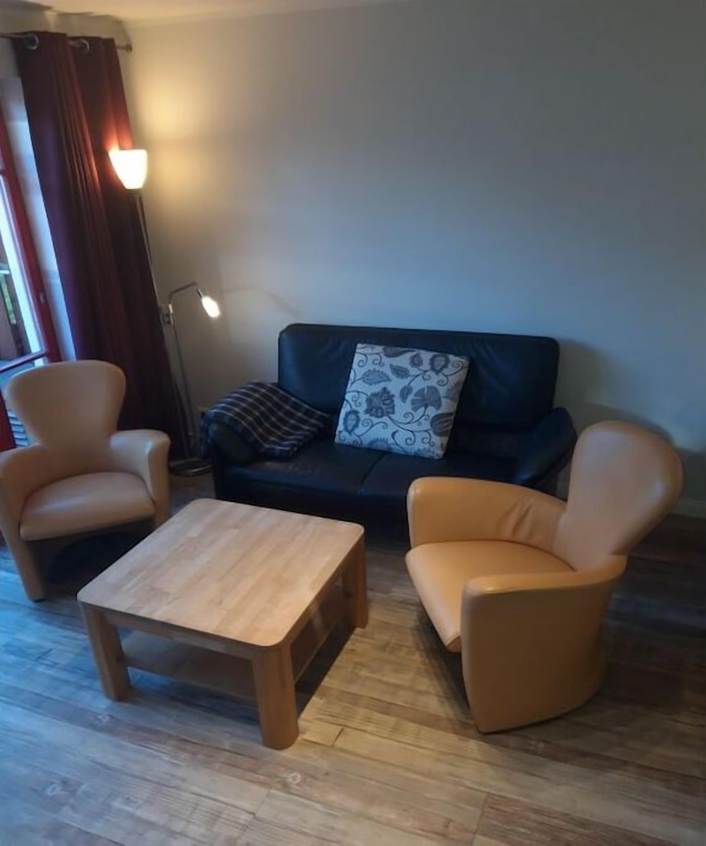 A living room with a sofa, two armchairs, a coffee table, and a floor lamp.
