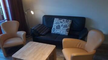 A living room with a sofa, two armchairs, a coffee table, and a floor lamp.