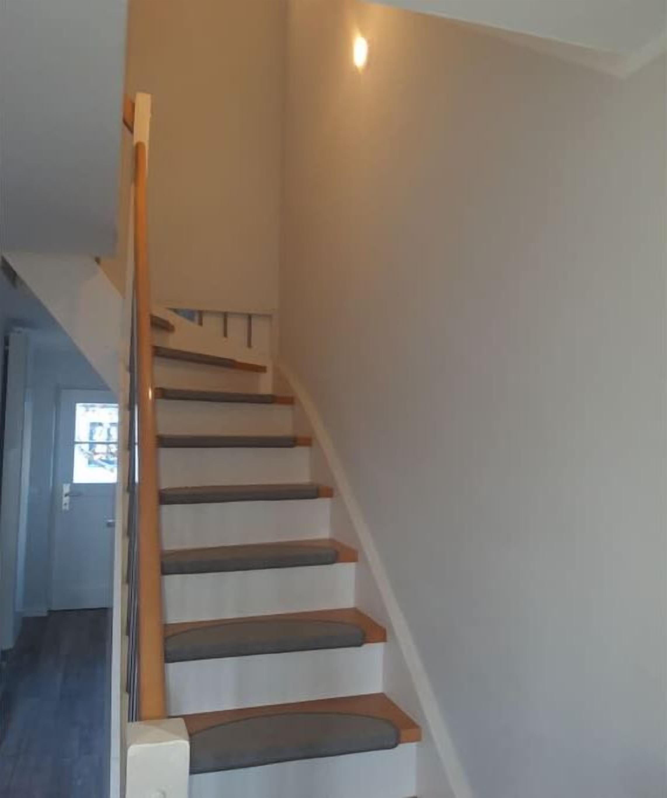 A staircase with wooden handrails and carpeted steps leading to an upper floor.