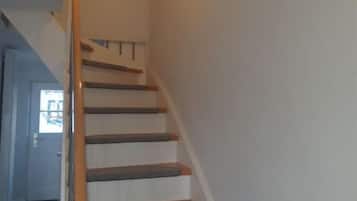 A staircase with wooden handrails and carpeted steps leading to an upper floor.