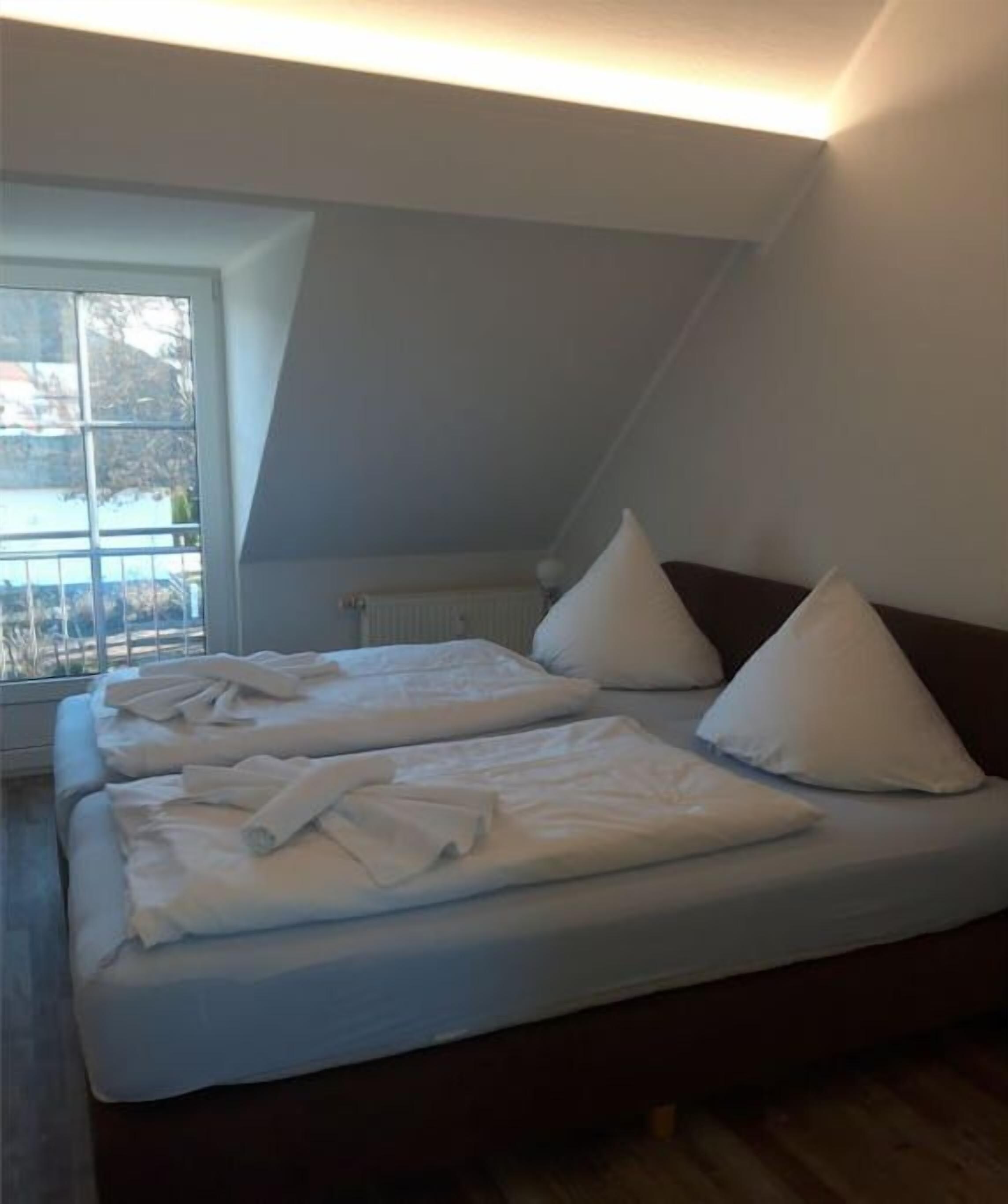 Een slaapkamer met een groot bed, een raam en een schuine kap.