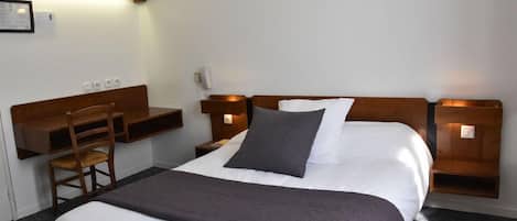 Une chambre d’hôtel avec un lit, des tables de chevet, un bureau et une chaise.