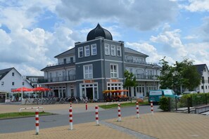 Een meerhoog gebouw met een opvallende zwarte koepel, een overdekt terras en een parkeerplaats met fietsen.