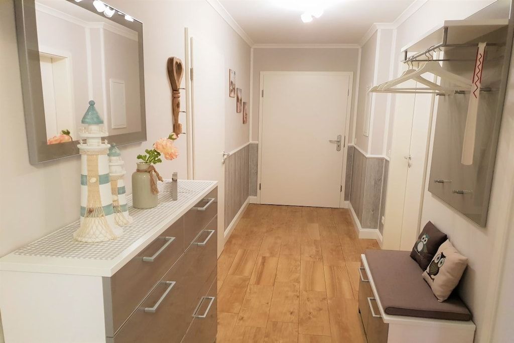 A hallway with a white bench, a mirror, and a coat rack.