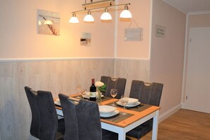 Een eetgedeelte met een houten tafel, vier stoelen en een fles wijn.