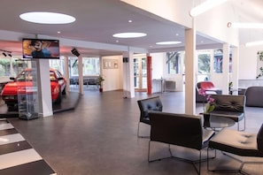 A modern interior with a reception area, seating, and a car display. - Enzo Trappes Versailles (Trappes)