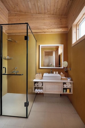 A bathroom with a wooden ceiling, a glass shower enclosure, a sink with a mirror, and towels on shelves. - Bangaram Island - Ihcl Seleqtions (Bangaram Island)