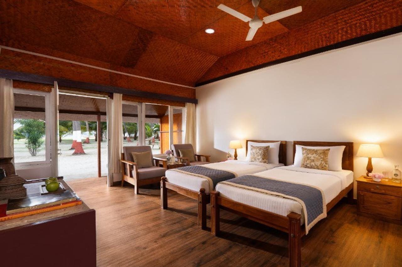 A hotel room with two beds, a ceiling fan, and a view of the outdoors.