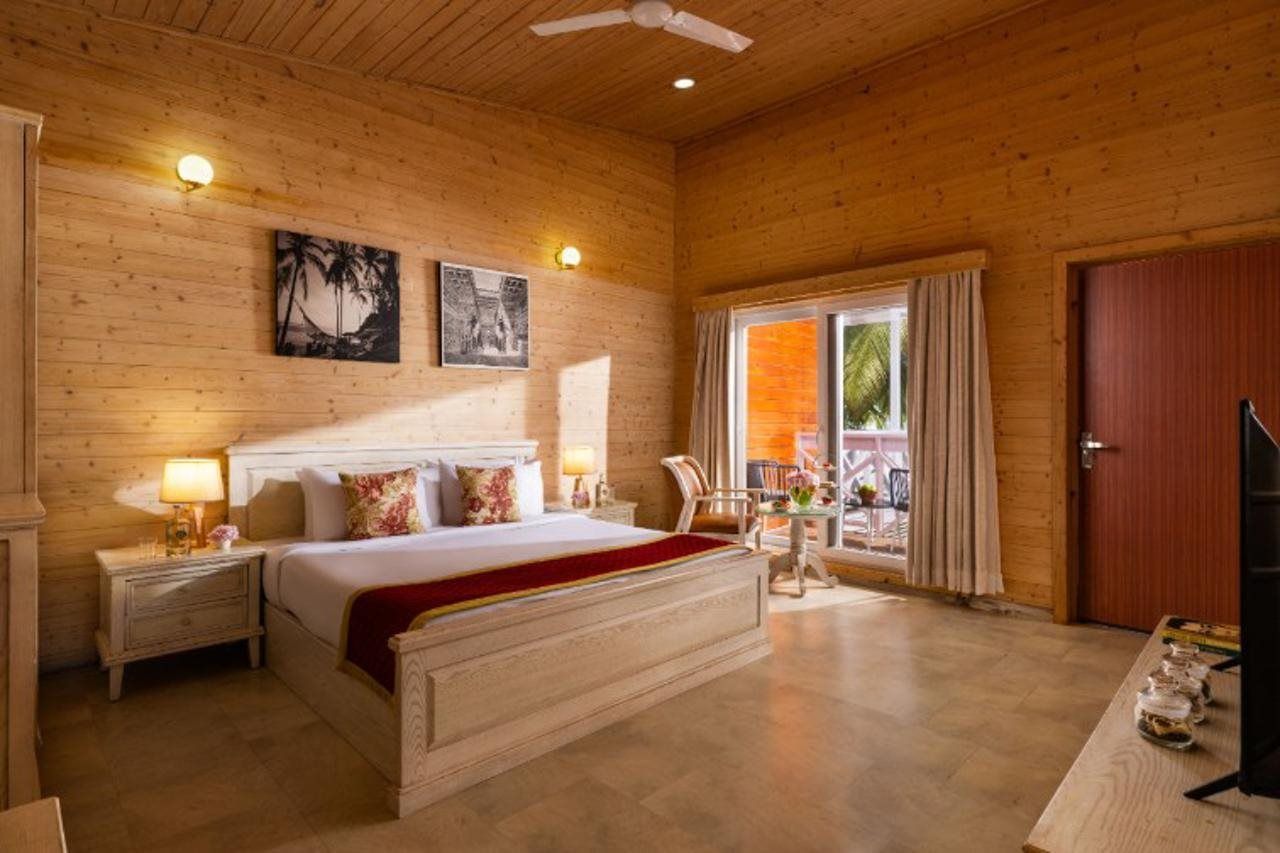Habitación con paneles de madera, una cama, mesitas de noche, un televisor y una ventana con cortinas.