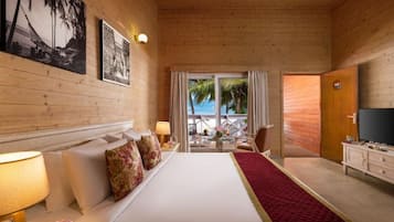 Una camera d'albergo con un letto, una TV, una scrivania con una sedia e una finestra vista palme.
