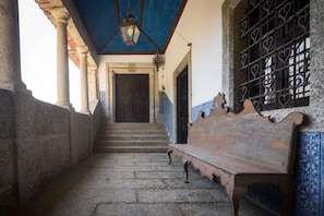 Un pasillo con un banco de madera, una escalera y una pared con rejas en forma de corazón.