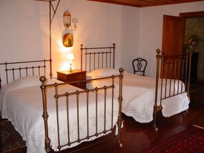 Ein Zimmer mit zwei Betten, einem Nachttisch, einer Wandlampe und einem Sessel.