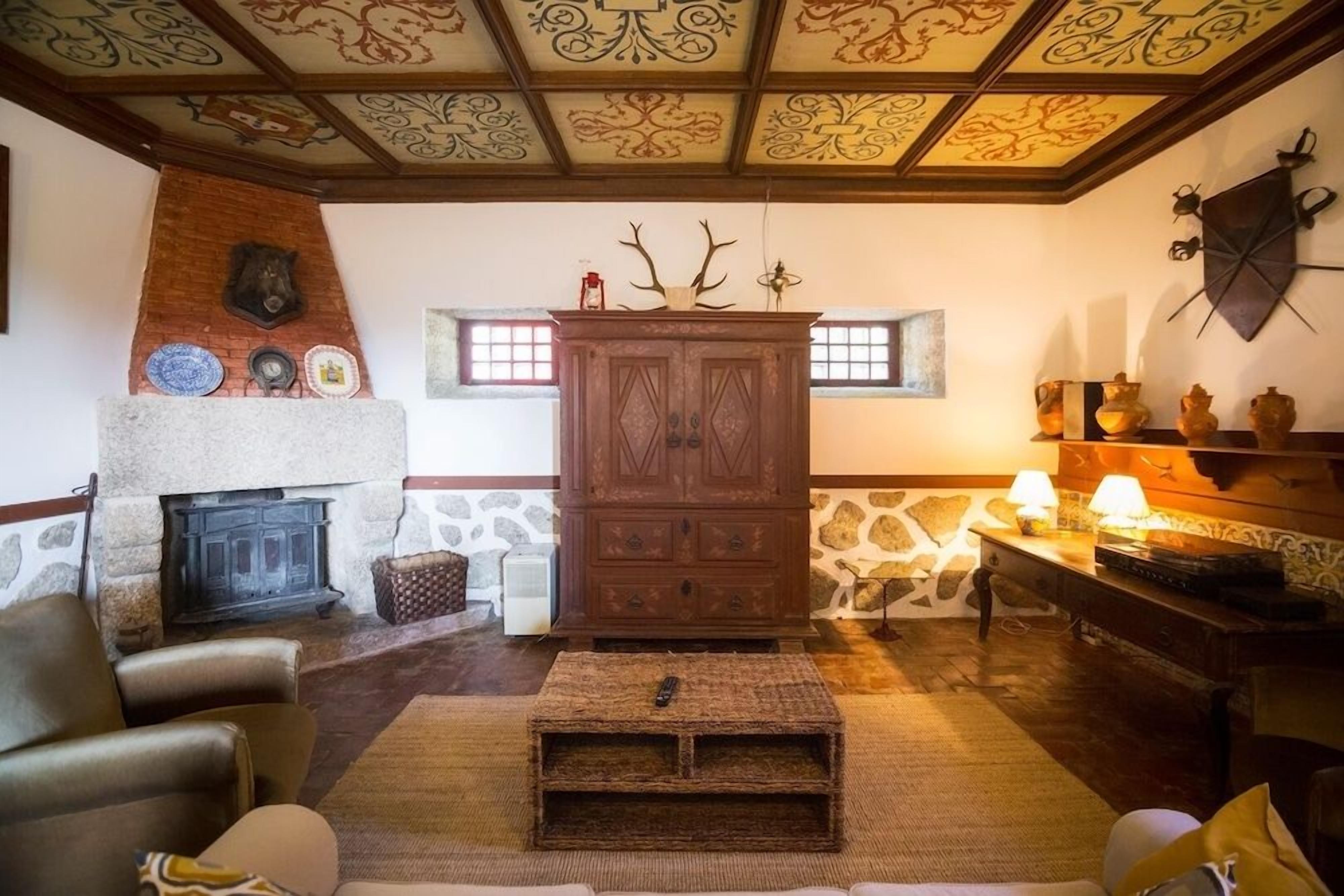 A cozy living room with a fireplace, a wooden cabinet, and a stone wall.