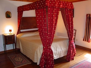 Un dormitorio con cama con dosel, una mesita de noche, una lámpara y una alfombra.