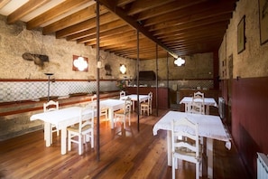 Un comedor con mesas y sillas de madera, una pared de piedra y un techo de madera.