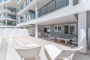 A modern outdoor lounge area with white furniture, a seating arrangement, and a view of the building's exterior. - AMPHORA BEACH RESIDENCE 2476 MANILVA (Manilva)