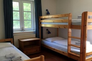 Ein Schlafraum mit Etagenbett, Fenster, Nachttisch und Lampe.