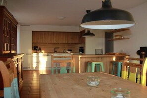 Eine Küche mit Holzschränken, einer zentralen Kochinsel und einem Essbereich mit Tisch und Stühlen.