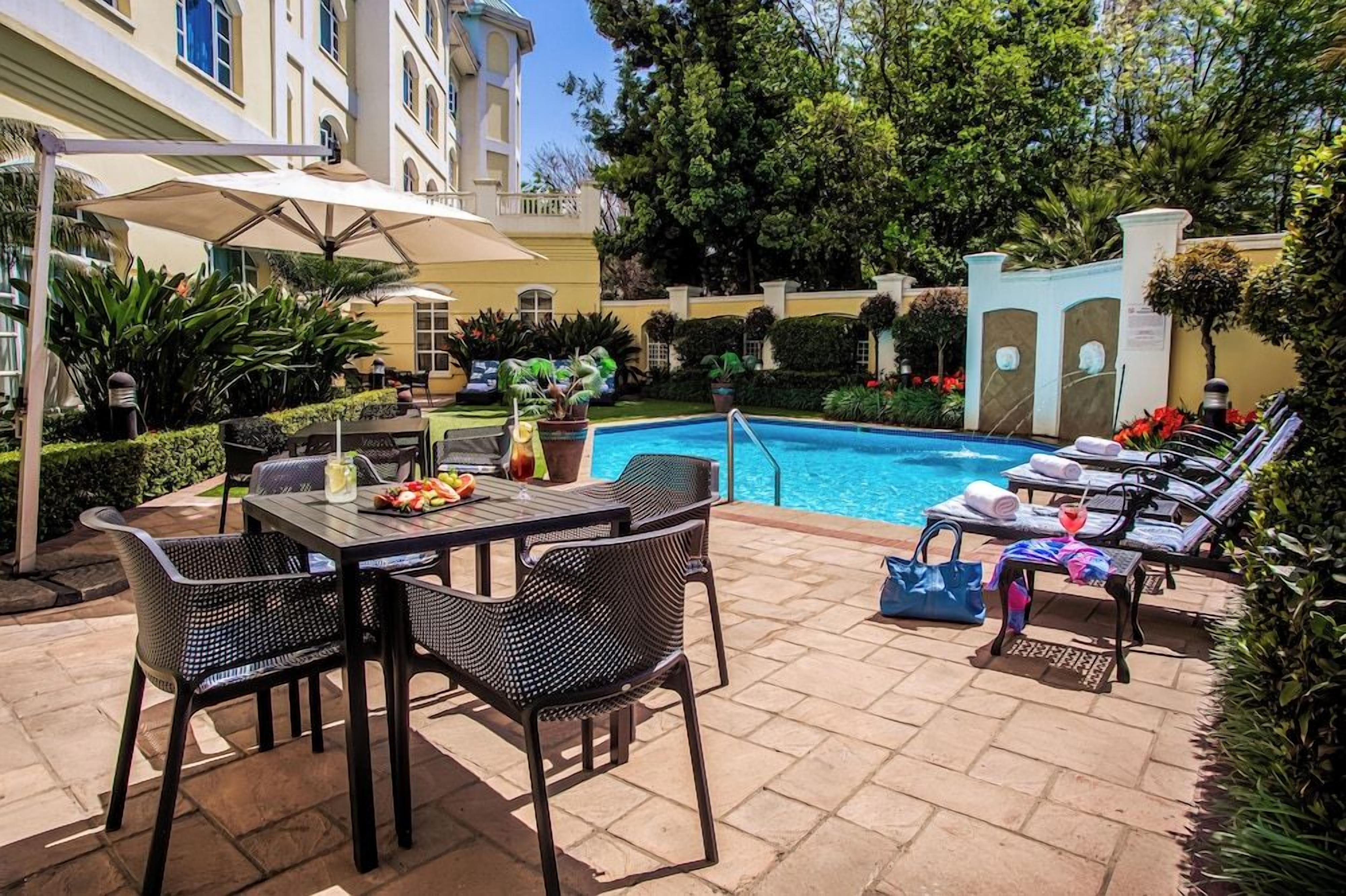 A poolside area with a table, chairs, and lounge chairs.