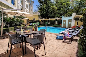 A poolside area with a table, chairs, and lounge chairs.