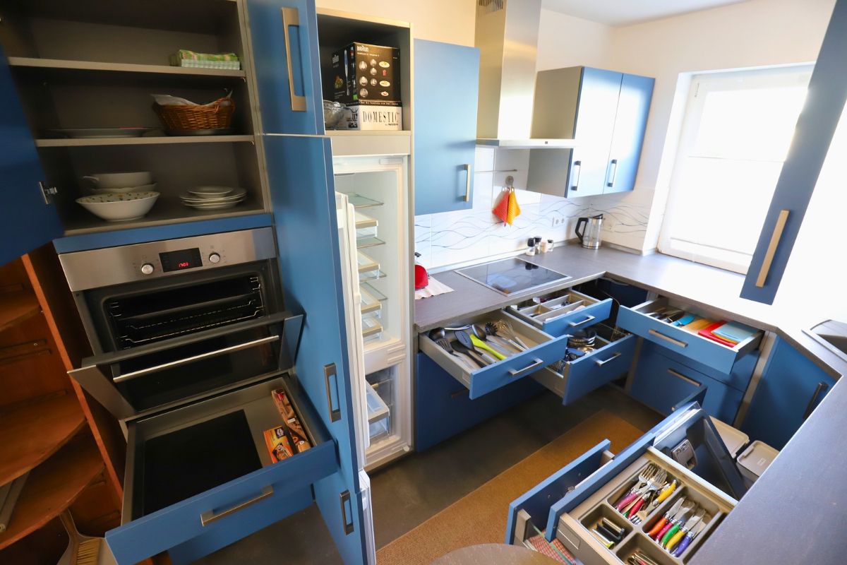 Cozinha com eletrodomésticos embutidos, armários abertos e janela.