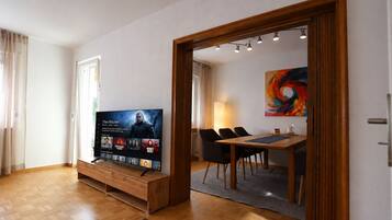 Ein modernes Wohnzimmer mit einem Flachbildfernseher, Holzmöbeln und einem Essbereich mit Stühlen und einem Tisch.