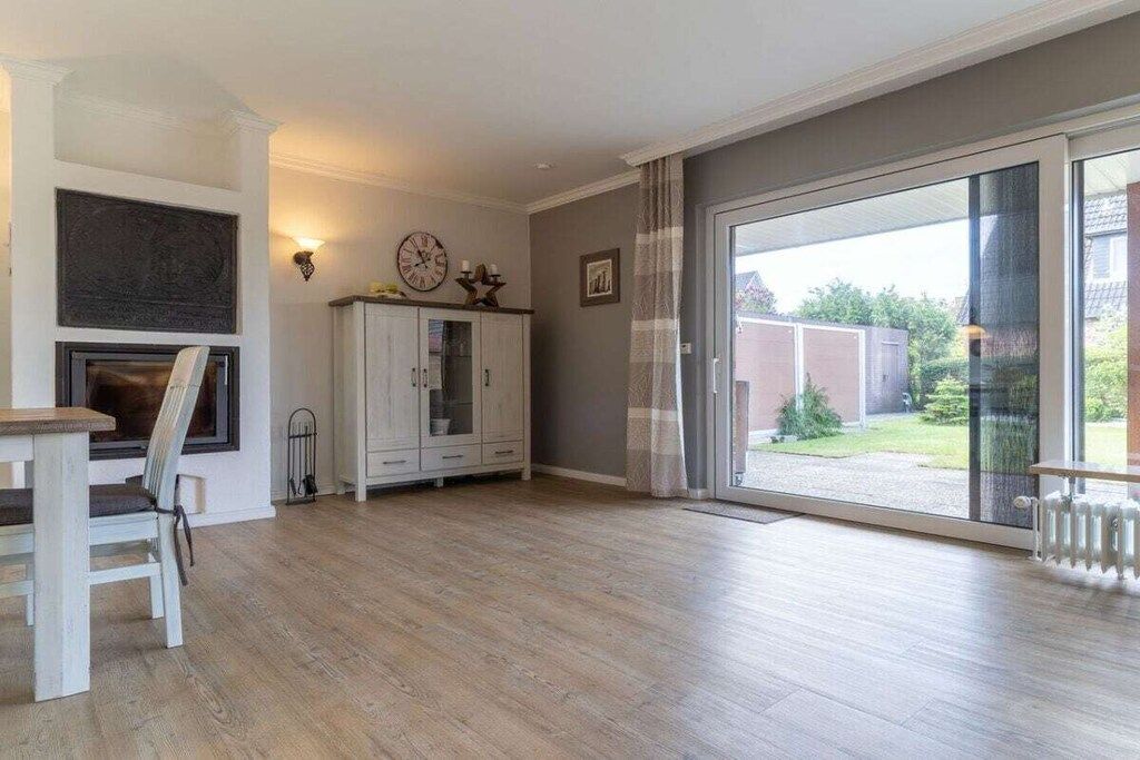 A spacious living room with a fireplace, a dining area, and a sliding glass door leading to a garden.