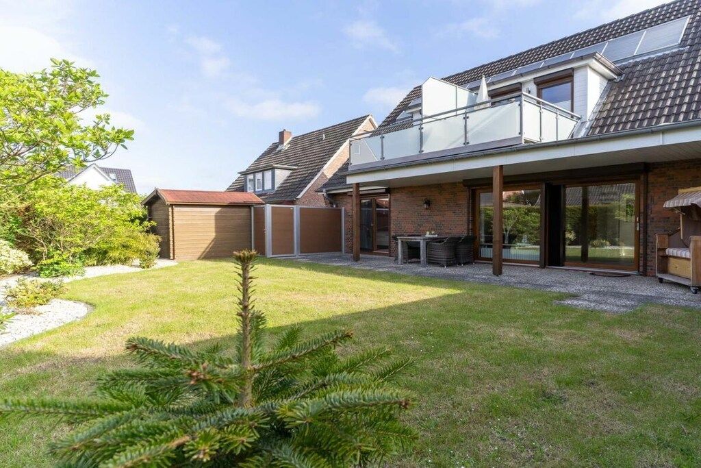A residential property with a covered patio, a brick exterior, and a small garden with a coniferous tree.