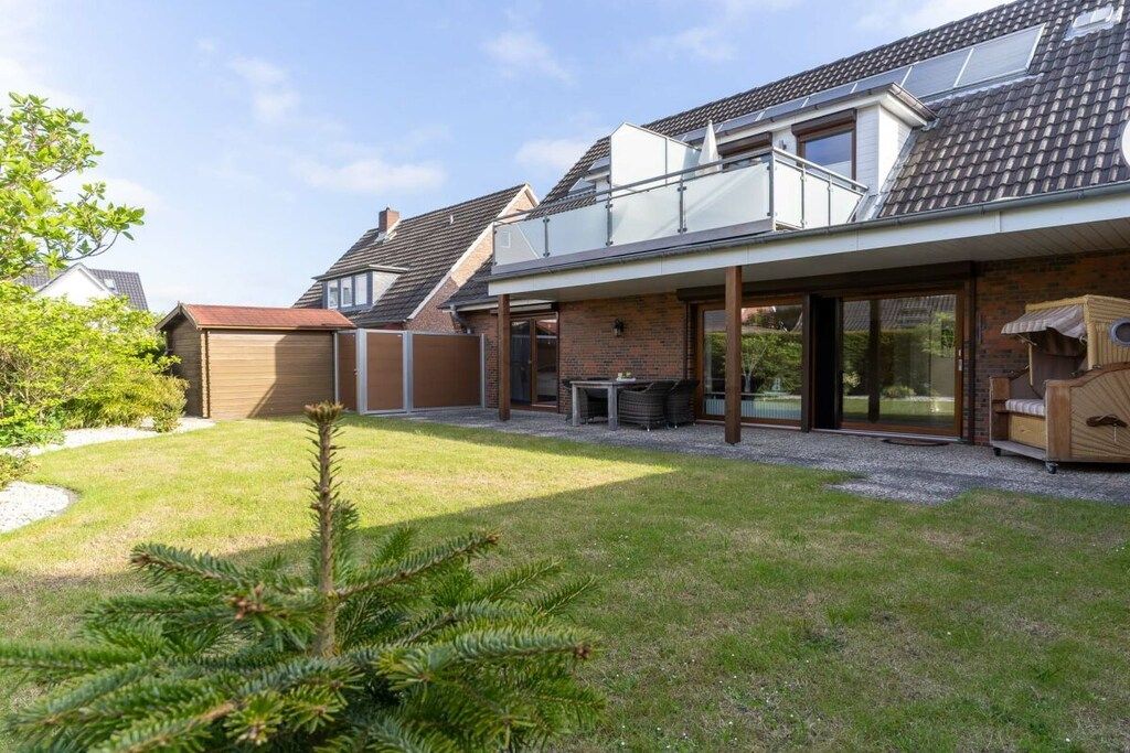 A modern house with a covered patio, a garage, and a well-maintained lawn.