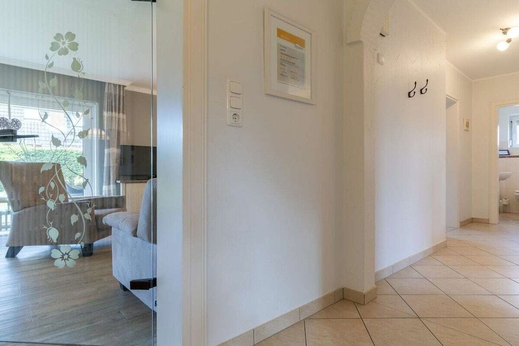 A hallway with a sofa, a framed certificate on the wall, and a tiled floor.