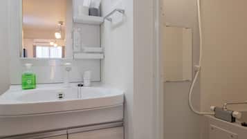 A modern bathroom with a white sink, mirror, and a shower area.