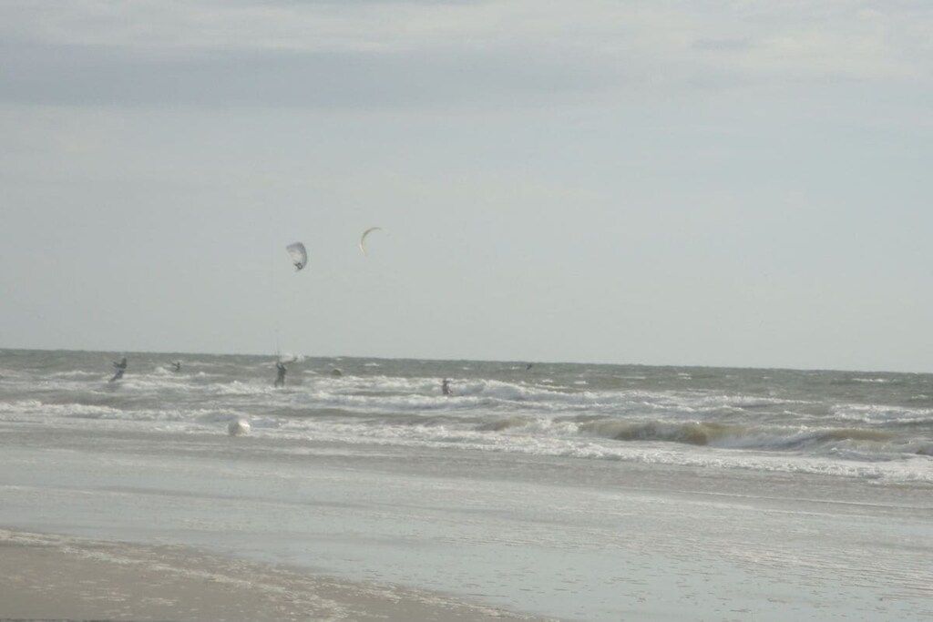 A beach with waves and people in the water.