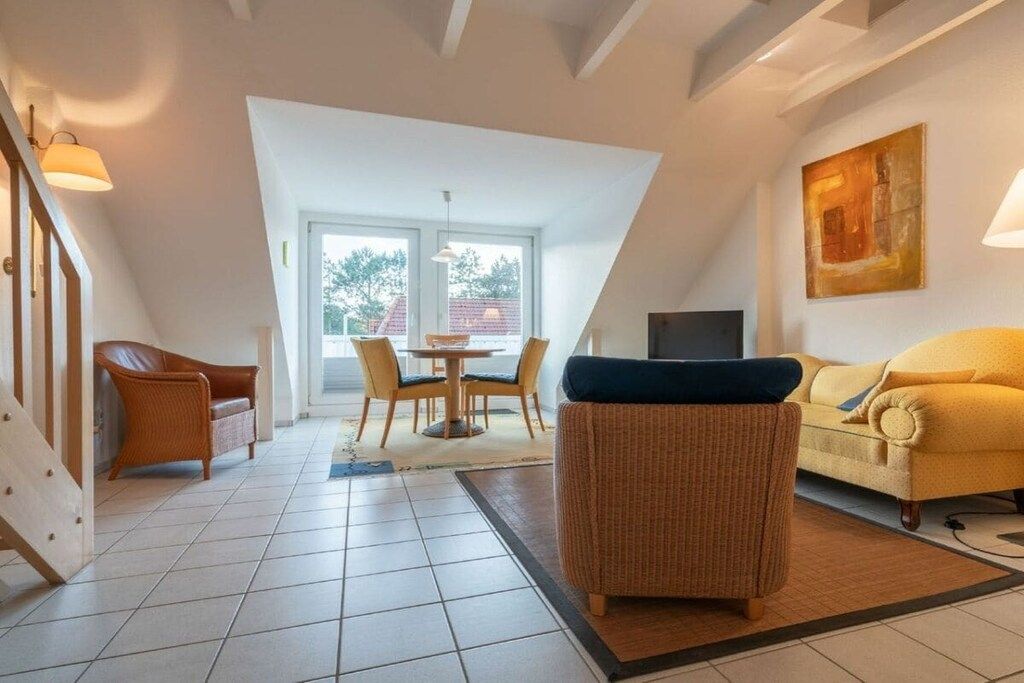 Un salon moderne comprenant un coin repas, un canapé, un fauteuil et un téléviseur.
